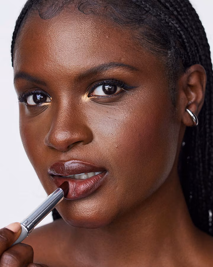 A close up shot of a model putting on a black honey lipstick 