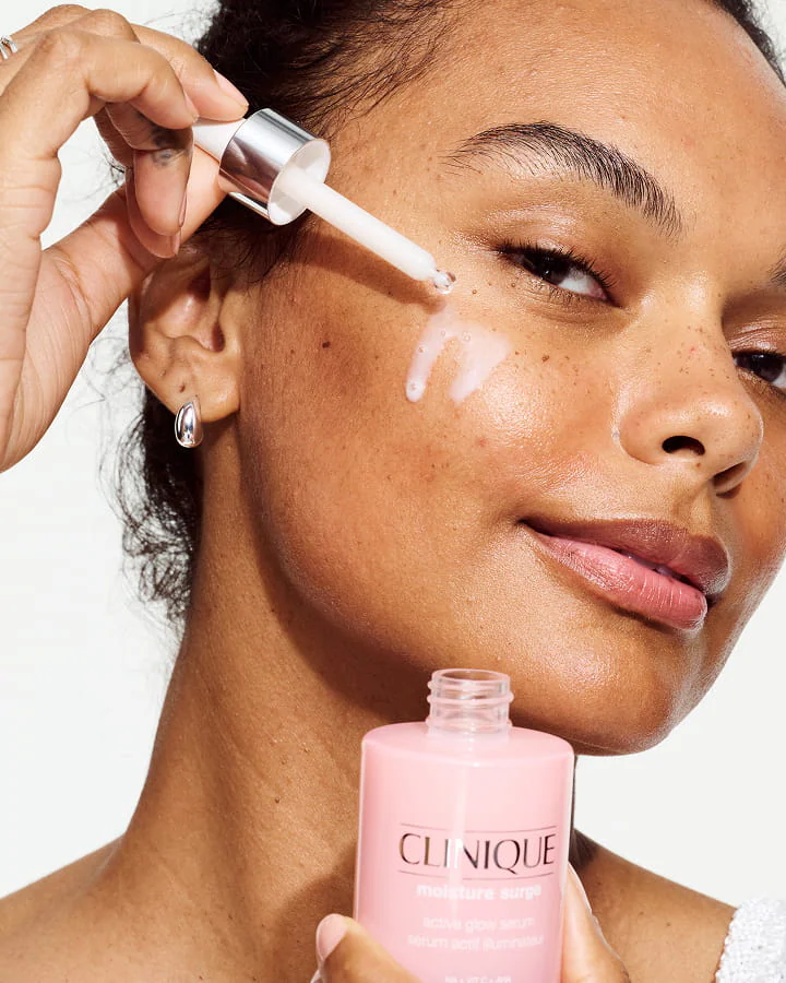 Close up of model applying Moisture Surge Serum to skin, focusing on product texture